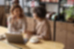two individuals sitting in a cafe at a computer