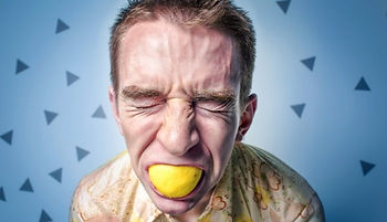 a person with a disgusted face with a lemon in their mouth